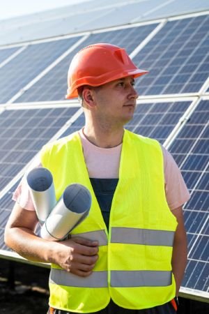 Mann mit Bauplänen und Solarpanelen